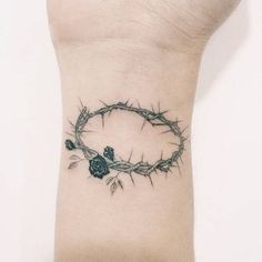 a tattoo on the wrist of a person with a crown of thorns around it