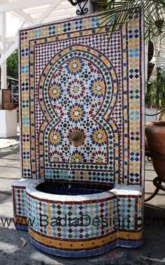 a colorful fountain in the middle of a courtyard with tile work on it's sides