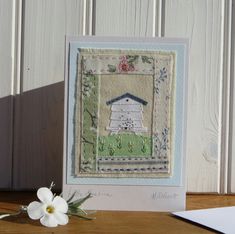 a white flower sitting on top of a table next to a card with a house