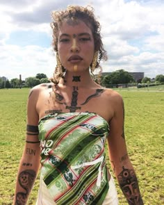 a woman with tattoos standing in a field