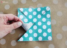 someone is making a paper origami christmas tree with polka dots on the table