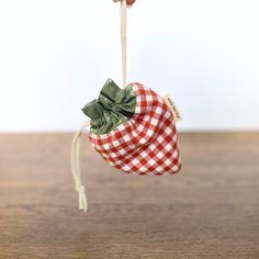 a small red and white checkered bag hanging from a string on a wooden table