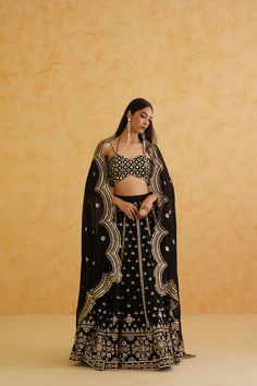 Black Lehenga Set | Deepika Chadha Deepika Chadha's stunning black georgette fabric lehenga, beautifully adorned with intricate crystal, patra and zari embroidered blouse. The black color adds a touch of glamour and sophistication to your look, while the georgette texture ensures you feel comfortable all day or night long. It is styled with a black net Dupatta to complete the look. Included in Purchase: Lehenga, Blouse & Dupatta Set Product Specification Color: Black Fabric: Georgette, Net Neckline: Spaghetti Strap Occasion: Bridal, Engagement, Formal Event Designer: Deepika Chadha Work: Hand Embroidery Sequins, Patra, Zari Care Instructions: Dry Cleaning only, No Flat Ironing on Hand Embroidery *Jewelry sold separatelyCustomization options:Can be customized in any color or blouse style No Black Semi-stitched Palazzo Set With Mirror Work, Semi-stitched Embellished Black Anarkali Set, Festive Black Pre-draped Saree With Cutdana, Wedding Black Pre-draped Saree With Intricate Embroidery, Black Georgette Bollywood Sharara, Black Georgette Sharara For Festive Occasions, Black Bollywood Style Georgette Sharara, Festive Black Georgette Sharara, Elegant Black Sharara For Festive Occasions