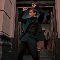 a man in a black suit and tie is standing outside an entrance to a building