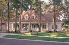 a white house with blue shutters in the front yard and trees lining the street