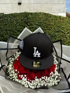 a los angeles dodgers cap sits on top of a bouquet of roses and baby's breath