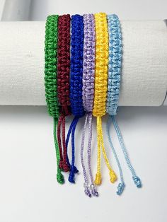 multicolored crocheted bracelets are displayed on a white napkin holder,