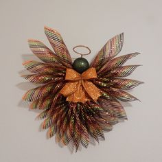 an ornament is hanging on the wall with leaves and a ball attached to it