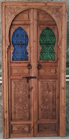 an intricately carved wooden door with blue and green glass inserts on the doors