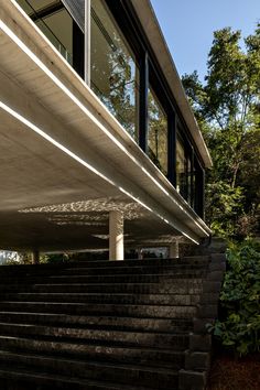 the stairs lead up to the upper level of this modern house, which is surrounded by trees and shrubs