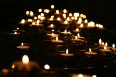 many lit candles are arranged in rows