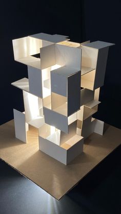 a sculpture made out of white boxes sitting on top of a table in the dark