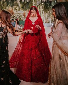 two women in red dresses standing next to each other and looking at something on the ground