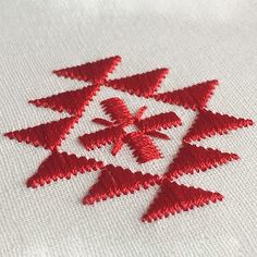 red thread on white fabric with small snowflakes in the center and two smaller ones at the bottom