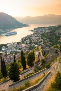 an aerial view of a town and the sea with mountains in the background at sunset