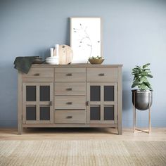 a wooden dresser sitting on top of a hard wood floor next to a potted plant