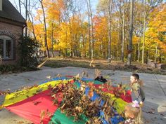 two children playing with a colorful kite in front of a brick house on a fall day