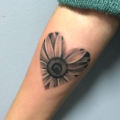 a black and white photo of a sunflower tattoo on the left inner arm or leg