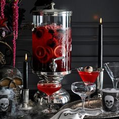 a table topped with glasses filled with red liquid and halloween themed decorations on top of it