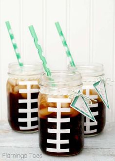 two mason jars filled with iced drinks and green straws on top of a table