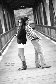 two people are standing on a bridge together