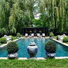 an outdoor pool surrounded by trees and lawn furniture with chairs around it in the grass