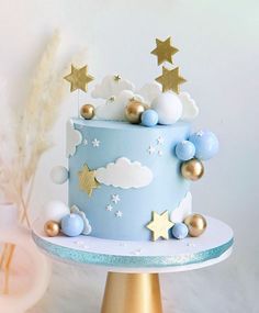 a blue cake with gold stars and clouds on top