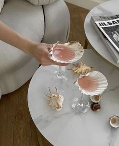 a person is holding some seashells on a table in front of a magazine