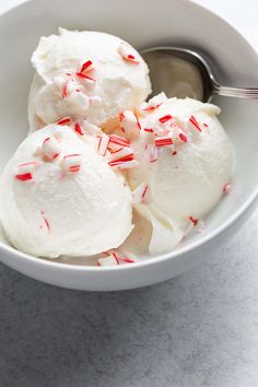 two scoops of ice cream with candy canes in a white bowl on a marble surface