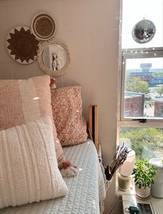 a bed with many pillows on top of it next to a window in a bedroom