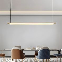 a modern dining room table with chairs and a long rectangular light fixture hanging over it