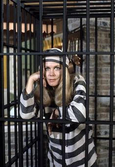 a woman in jail cell wearing a hat and holding her hand up to her face