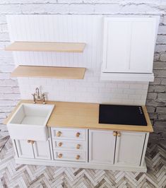 a kitchen with white cabinets and a black stove top in the center, next to a brick wall