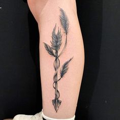 a tattoo on the leg of a woman with an arrow and snake wrapped around it