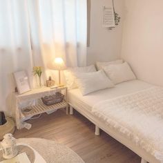 a white bed sitting in a bedroom next to a table with a lamp on it