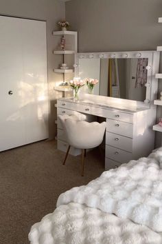 a bedroom with a white bed, desk and mirror on the wall next to it