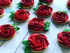 cookies decorated with red icing and green leaves are arranged on a white wooden surface