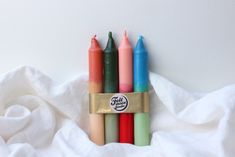 four different colored crayons are in a row on a white sheet with a sticker