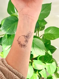 a woman's arm with a small bird tattoo on the left side of her wrist