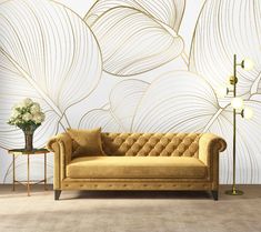 a living room with a couch, lamp and wallpaper that has gold leaves on it