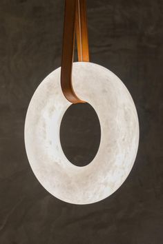 a white circular light hanging from a wooden hook on a black wall in a room