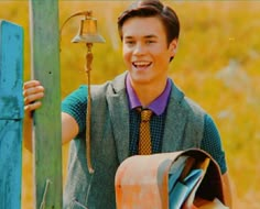 a young man is smiling and holding onto a pole with a bell on it,