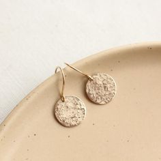 Sweet little discs of shimmering gold.  I have given the metal a "raw silk" texture.  It is subtle and unique.  Discs measure 1/2".  Total length 1".  Handmade shepherd hook earwires.  14k gold fill.  About 14k gold fill: 14K gold filled wire is a professional jewelers grade wire. Gold filled wire is not plated. It is a tube of solid 14K gold mechanically bonded to a brass or silver base. There is 100 times more gold in gold filled than in gold plate wire. This layer of gold must be a minimum of Gold Circle Earrings 14k Gold Filled, Gold Brass Round Disc Earrings, Gold Circular Earrings As Gift, Gold Circular Earrings For Gift, Gold Circle Earrings As Gift, Dainty Adjustable Gold Earrings, Gold Circular Earrings For Wedding, Gold Hammered Circle Earrings, Gold Round Disc Earrings For Pierced Ears