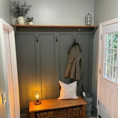 a room with a bench, coat rack and candle on the table in front of it