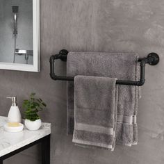 two towels hanging on a towel rack next to a bathroom sink with a mirror and soap dispenser