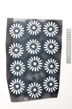 a piece of paper with white flowers on it and a ruler next to it,