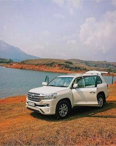 a white toyota land cruiser parked by the water