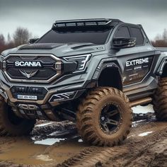 a grey truck driving through mud on top of a hill