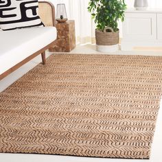 a living room area with a couch, rug and potted plant on the floor