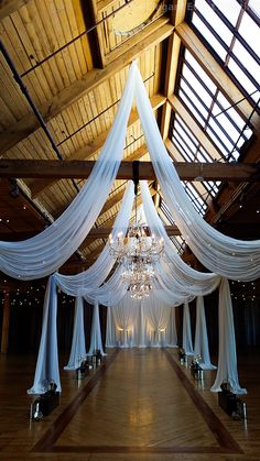 an indoor wedding venue with white drapes and chandelier hanging from the ceiling